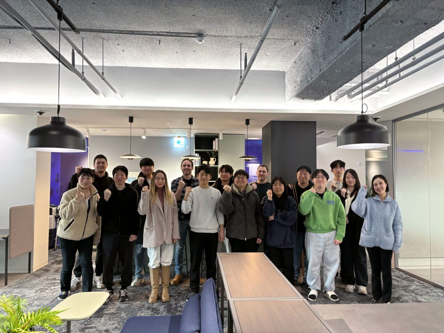 A group of people standing in a office posing for a group picture.